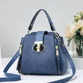 Détail du sac seau bleu marine avec dentelle florale et fermoir doré en forme de T - Bleu