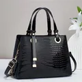 Elegante schwarze Handtasche mit Krokodilprägung und goldenen Metallelementen - Schwarz