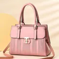 Pink striped leather handbag with golden hardware and adjustable strap shown on warm background - Pink