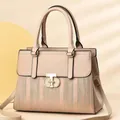 Nahaufnahme der beigen Handtasche mit goldenem Drehverschluss und Streifenprägung - Khaki