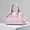 Bolso Boston acolchado rosa con hebilla de corazón dorada en soporte blanco minimalista - Rosa