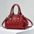 Bolso Boston acolchado rojo oscuro con logo de corazón dorado y correa ajustable - Granate