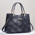 Detailed macro view of diamond-quilted denim texture and gold hardware on blue tote bag - Black