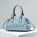 Detalle del bolso acolchado azul claro con cierre de corazón dorado en expositor - Azul