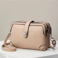 Detailed view of beige crossbody bag featuring triple zipper compartments and lychee texture - Khaki