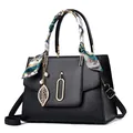 Black pebbled leather tote bag with elegant silk scarf handle and pearl leaf pendant - Black