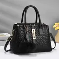Elegant black woven handbag with gold hardware, pom-pom charms, and detachable shoulder strap - Black