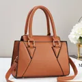 Close-up of caramel litchi grain leather handbag with geometric triangle stitching - Earthy Yellow