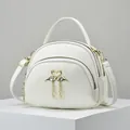White semi-circular crossbody bag with litchi grain leather and swan tassel charms - Off White