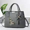 Détail du sac à main en cuir gris avec broderie florale élégante et accents en métal doré - Gris