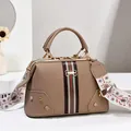 Detailweergave van de kaki handtas met groen-rood lint en geborduurde schouderriem - Khaki