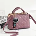 Detail of purple quilted handbag featuring gold studs, round handles, and pompom charm - Deep Purple with Golden Rivets