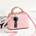 Detailed shot of pink quilted crossbody bag with gold studs and a fuzzy pompom charm - Pink