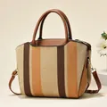 Detail of striped canvas tote showing brown leather handles and golden metal hardware - Earthy Yellow