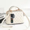 Chic beige quilted square handbag with gold rivets, three zippers, and plush pompom charm - White