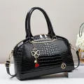 Elegant black crocodile-patterned shell bag with golden hardware and glossy finish - Black