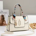 Elegante cremefarbene Handtasche mit Seidentuch am Griff und goldenem Blattanhänger - Gebrochenes Weiß