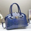 Détail du sac à main en cuir verni bleu foncé à relief crocodile et accents dorés - Bleu
