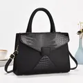 Sac à main noir en cuir croco avec détails dorés et bandoulière sur bureau - Noir