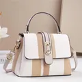 Detalle de textura, cierre ovalado dorado y correa de cuero marrón en bolso de mujer - Blanco Roto
