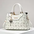 White monogram tote bag with gold metal handles and heart charm accessory - White