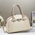 Detailed view of cream-colored crocodile embossed handbag with golden lock and chain - Khaki