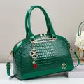 Detail of green crocodile embossed faux leather bag with gold heart clover charms - Green