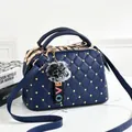 Detail of dark blue quilted handbag with gold studs and a grey faux fur pompom charm - Dark Blue