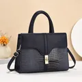 Detail of navy blue tote bag featuring crocodile pattern texture and gold square lock - Dark Blue