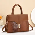 Detail of warm brown tote featuring crocodile print and pebble texture splicing with gold lock - Earthy Yellow