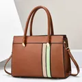 Detail view of large tote bag with color-block stripes and protective metal base feet - Earthy Yellow