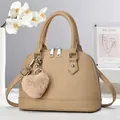 Detail of khaki shell handbag with lychee texture and plush heart charm on a display stand - Khaki