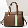 Detail of contrast stripe design and protective metal feet on a brown tote handbag - Coffee
