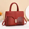 Detail of red crocodile texture tote with golden twist lock and luxury faux leather - Red