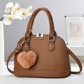 Detail of brown litchi pattern shell bag featuring double zippers and plush heart charm - Dark Khaki