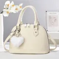 Detail of creamy white litchi pattern shell bag with plush heart pendant and silver hardware - Off White