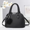 Close-up of black litchi grain shell bag with silver dual zippers and fuzzy ball charm - Black