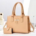 Detailed view of beige tote bag set with swan metal charm and leather texture - Khaki