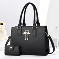 Detail of black lychee leather tote bag set with golden swan pendant and matching wallet - Black