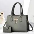 Detail of dark grey litchi grain tote with gold swan hardware and pearl tassel - Gray