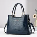 Bolso de mano azul oscuro con relieve de cocodrilo, herrajes dorados y logo Donbooly - Azul