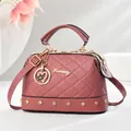Close-up of quilted pattern on pink Boston bag with golden studs and heart charm - Pink
