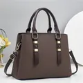 Detailed macro view of dark brown textured tote bag with golden hardware and handles - Coffee