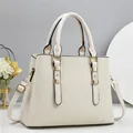 Close-up of cream handbag featuring vertical ripple texture and champagne gold hardware - Off White