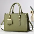 Detail van avocado groene lederen shopper met goudkleurige hardware en zijvouw ontwerp - Groen