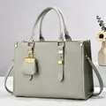 Detail of grey lychee leather tote bag with gold hardware and hanging charm - Gray