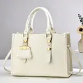 Detail of white tote bag with lychee texture, golden hardware and mini pendant charm - Off White