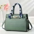 Detalle de bolso verde claro grabado de cocodrilo con pañuelo de seda y cierre dorado - Verde