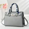 Detalle del bolso tote gris con motivo de cocodrilo, herrajes dorados y elegante pañuelo - Gris