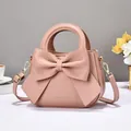 Elegant pink women handbag with large decorative bow and gold-tone hardware detail - Pink